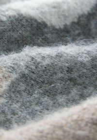 Soft wool fabric in gray and cream, featuring a textured surface with varying shades and slight fuzziness throughout, creating a tactile look.