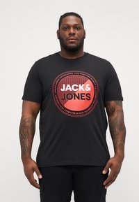 T-shirt nera in cotone con una grafica circolare rossa e il testo "JACK&JONES". Maniche corte e design a girocollo.