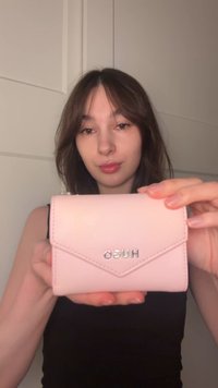 Roze portemonnee van nep leer met een klepsluiting, voorzien van een zilveren logo. Het ontwerp heeft gestikte accenten en een slank, rechthoekig model.