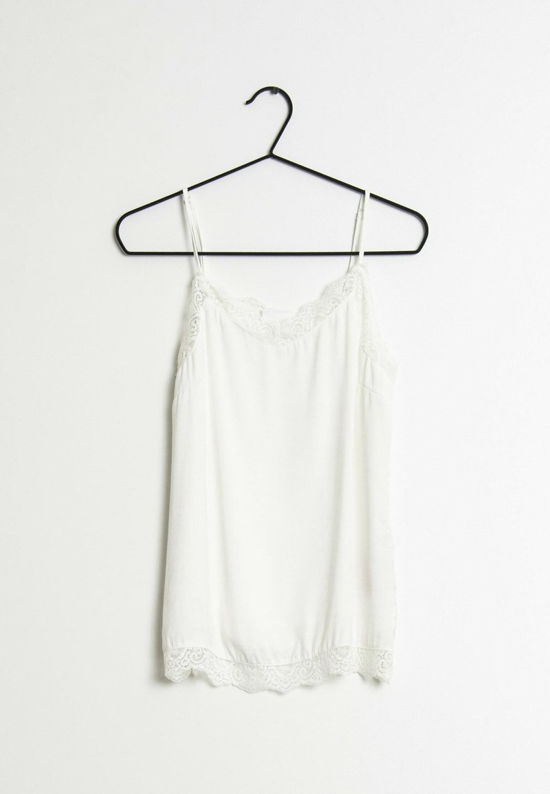 Vit linne hängande på en svart krok, med spetsdetaljer vid halsringningen och fållen, samt tunna justerbara band och en slät yta.