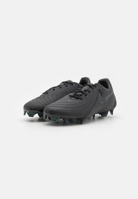 Crampons de football noirs avec une tige texturée, un design élégant, un système de laçage et des crampons moulés pour une adhérence sur les surfaces herbeuses.