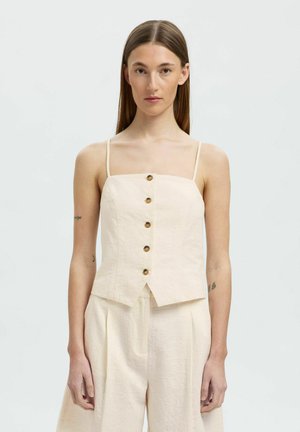Cremefarvet cropped top med tynde stropper, frontknapper og en struktureret design, der har et let tekstureret stof.