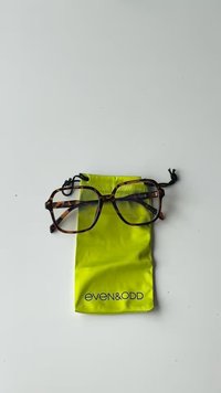 Des lunettes rectangulaires en écaille de tortue reposant sur une pochette à cordon de couleur vert citron vif, avec le nom de la marque "even&odd" imprimé en noir.