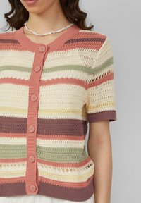 Strickjacke mit kurzen Ärmeln, mit horizontalen Streifen in Creme, Rosa, Grün und Braun. Fünf-Knopf-Verschluss und offene Strickdetails.