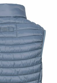 Helles blaues Pufferweste mit horizontalen gesteppten Paneelen, hohem Kragen und einem kleinen Logo-Tag auf dem oberen Rücken. Glatte, glänzende Textur.