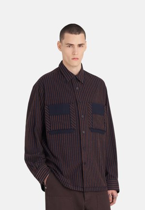 Chemise rayée en marine foncé avec des rayures orange rouille, dotée de deux poches à rabat, d'une fermeture à boutons et d'un design de col classique.