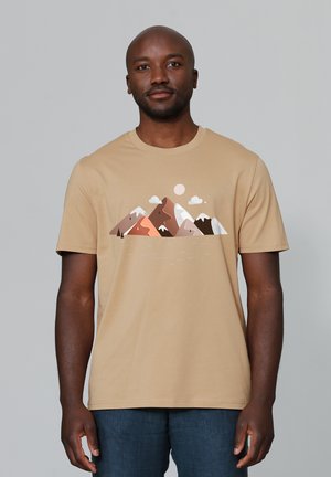 Beige T-shirt gemaakt van zacht katoen, met een bergafbeelding in verschillende aardetinten en subtiele illustraties van wolken en de zon.