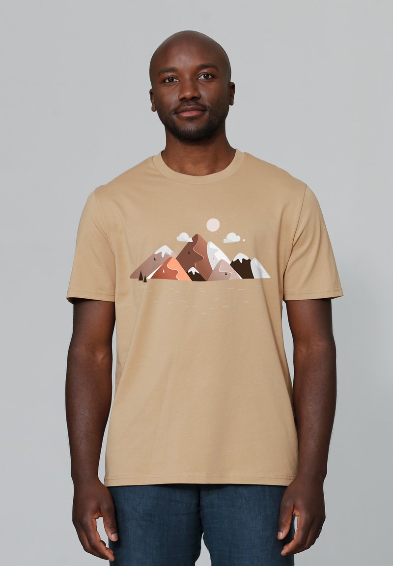 Beige T-Shirt aus weicher Baumwolle, mit einem Bergmotiv in verschiedenen erdigen Farbtönen und einer dezenten Darstellung von Wolken und Sonne.