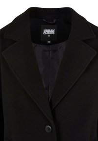 Svart ullblazer med fétt krage, enkel knappelukking og satengfôr; merket viser "Urban Classics," størrelse XS, laget i Kina.