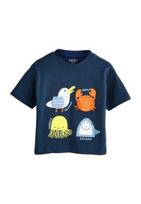 Mörkblå bomullströja med fyra färgglada djurillustrationer: en mås, en krabba, en manet och en haj, med textetiketter under varje.