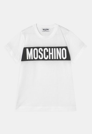 Biała bawełniana koszulka z czarnym poziomym paskiem i wyraźnym białym napisem "MOSCHINO" na klatce piersiowej. Krótkie rękawy, okrągły dekolt.