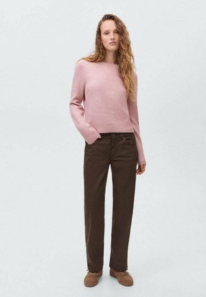 Suéter de punto de color rosa claro con un diseño corto, combinado con pantalones rectos marrón oscuro. El modelo lleva zapatos de slip-on marrones.