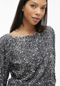 Grijze sequentop met een ronde hals, een losse pasvorm en een gestructureerd oppervlak dat is gecreëerd door overlappende sequins.