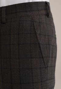 Pantalons à carreaux marron en tissu texturé. Présentent une jambe fuselée, une poche latérale et une taille ajustée avec passants de ceinture.