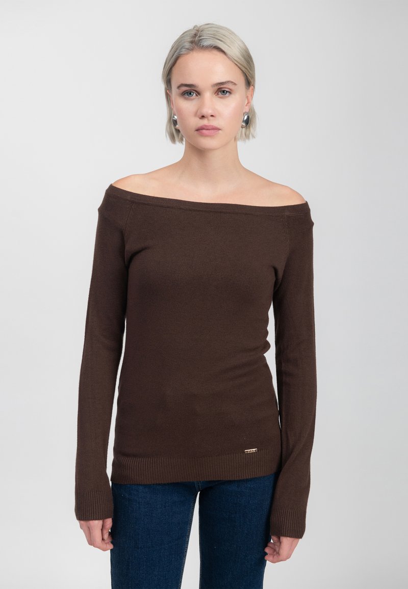 Brauner, schulterfreier Pullover aus weichem Material mit langen Ärmeln und geripptem Saum; beinhaltet ein kleines metallisches Logo nahe dem Saum.