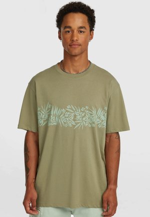 Oliwkowa koszulka z krótkim rękawem wykonana z bawełny, zdobiona jasnoniebieskim kwiatowym nadrukiem na wysokości klatki piersiowej. Luźny krój z okrągłym dekoltem.