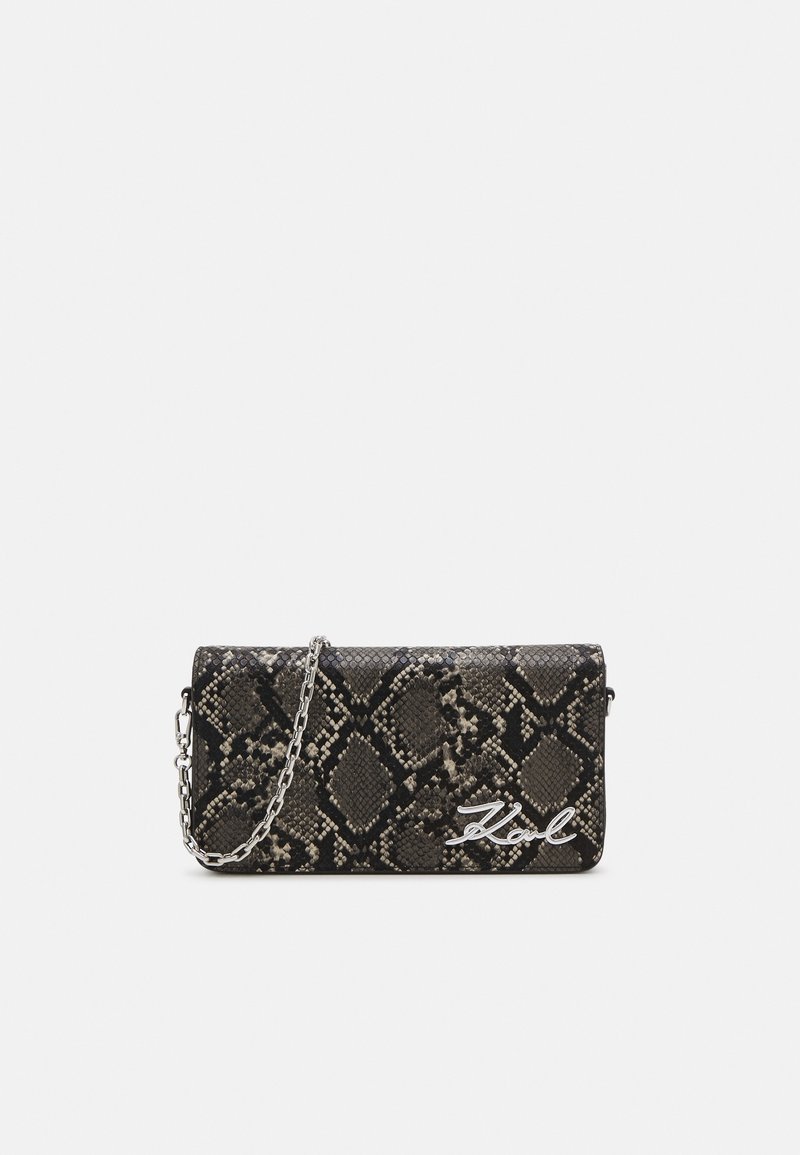 Musta ja harmaa tekonahkainen kädessä pidettävä laukku, jossa on hopeinen ketjuhihna, painokuviointi ja hopeinen logokoriste etupuolella.