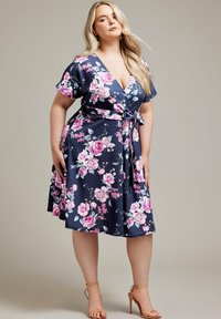 Vestido envolvente floral en color navy con mangas cortas, que presenta rosas rosas y hojas verdes. La cintura está ajustada con un lazo, creando una silueta fluida.