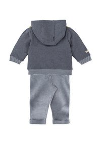 Sudadera gris con capucha y pantalones grises a rayas. Ambos hechos de una tela suave, con puños a rayas y una pequeña etiqueta en la sudadera.