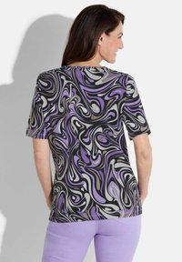Mehrfarbiges Kurzarmoberteil mit wirbelndem Muster in Schwarz, Lila und Grau. Weicher, leichter Stoff mit lockerer Passform.