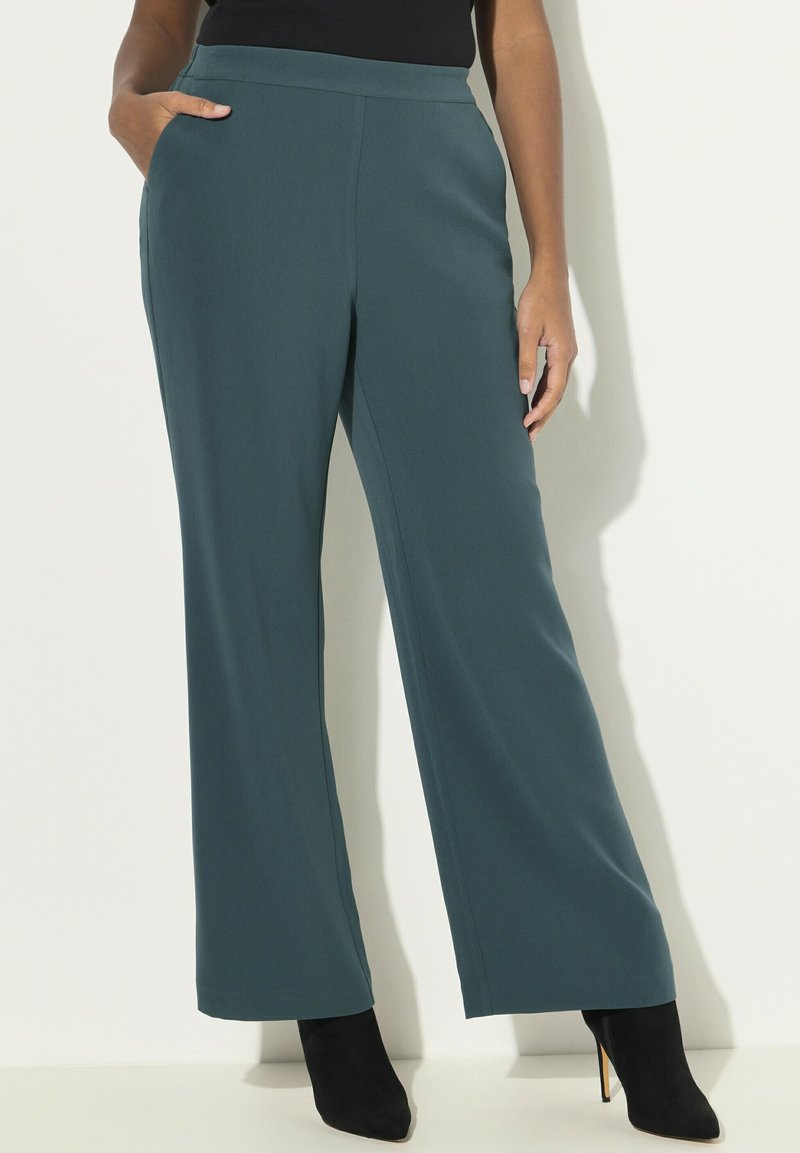 Pantaloni larghi color turchese realizzati in tessuto morbido, con vita media e tasche, abbinati a scarpe con tacco nere.
