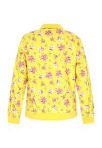 Giacca a fantasia floreale con sfondo giallo brillante, polsini elasticizzati e orlo a coste. Il materiale sembra liscio e leggero.