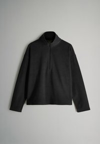 Čierny fleecový pulóver s vysokým golierom a krátkym zipsom. Má dlhé rukávy a voľný strih, vyrobený z mäkkej textúrovanej tkaniny.