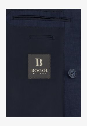Forro interior de blazer azul marino con etiqueta cosida que dice "B Boggi Milano" y un botón a juego con el mismo texto.