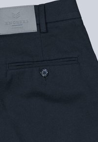 Dark blue pants with a smooth texture, featuring a back pocket with a black button and a grey leather tag embossed with "ENGBERS GERMANY."