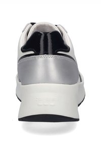 Bílé tenisky s černými a stříbrnými akcenty. Mají hladký kožený povrch, strukturovaný zadní panel a silnou, polstrovanou podešvi.