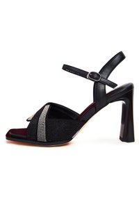 Černé sandály na vysokém podpatku mají strukturovaný svršek s kamínkovými akcenty, čtveratou špičku a nastavitelné řemínky kolem kotníku.