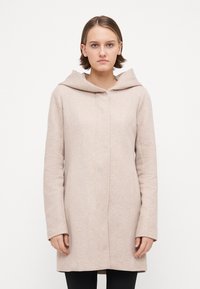 Helle beige Jacke mit Kapuze, maßgeschneiderter Schnitt, leicht strukturierten Stoff, langen Ärmeln und geradem Schnitt bis zur Mitte des Oberschenkels.