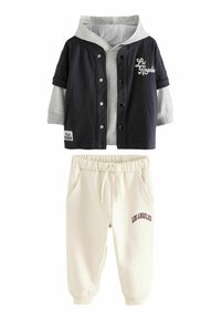 Veste de sport à superpositions bleu marine et gris avec des boutons blancs et l'inscription "Los Angeles". Pantalons de survêtement crème avec taille élastique et broderie "LOS ANGELES".