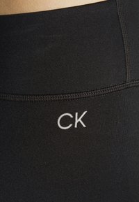 Zwarte rekbare leggings met een hoge tailleband. Voorzien van een witte "CK"-logo op de tailleband, een gladde textuur en versterkte stiksels.