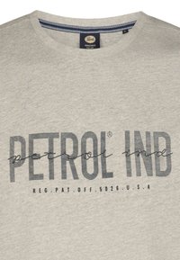 Lys grå bomuld t-shirt med fed sort tekst "PETROL IND" med en stribet accents. Rund hals med kontrasterende marineblå kant.