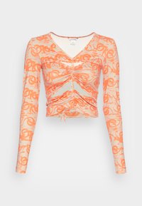 T-shirt de manga longa, com decote em V, na cor laranja, com uma estampa gráfica, apresentando franzidos na parte frontal e seções recortadas para um design justo.
