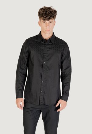 Camicia nera con bottoni, realizzata in tessuto testurizzato, caratterizzata da un sottile motivo geometrico sulla parte anteriore, maniche lunghe e orlo curvo.
