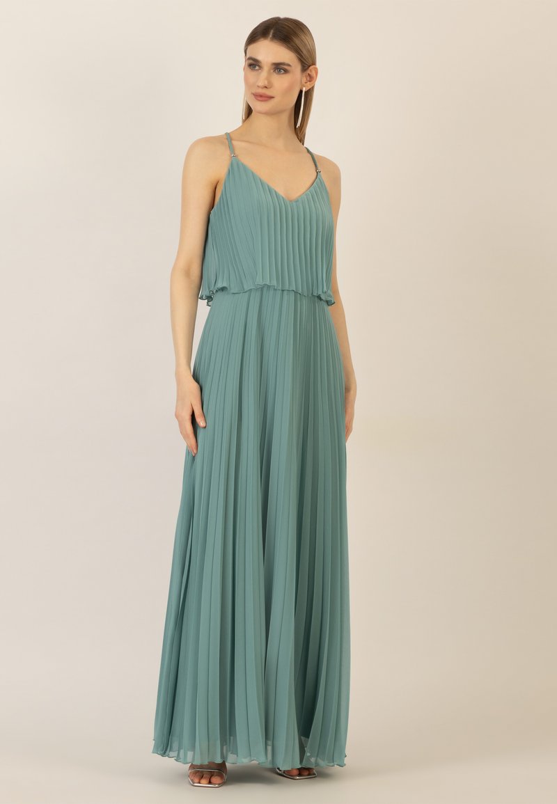 Plisségrote jurk in zachte teal stof, met een V-hals en delicate straps met accenten. Vloeiende silhouet tot op de vloer.