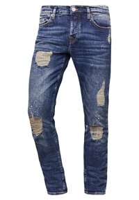 Siniset farkut slim fit -mallissa, joissa on useita kuluneita alueita, vaaleaa haalistumista ja metallinappiyksityiskohtia.