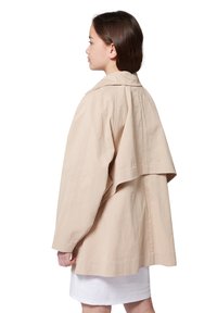 Chaqueta beige de gran tamaño con una gran solapa trasera, que incluye un cuello y mangas largas. Tejido suave y ligero sin patrones ni herrajes visibles.