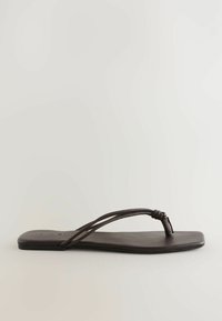 Sandale plate en cuir lisse de couleur marron. Dotée de fines lanières avec un détail de nœud et d'un design de semelle carrée minimaliste.
