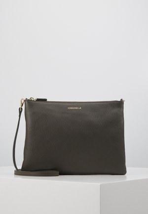 Zwart gestructureerd leren polstasje met gouden ritssluiting en klein goudkleurig logo "COCCINELLE" aan de voorkant.