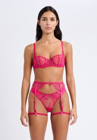 Gorący różowy zestaw bielizny z koronkowymi detalami, biustonosz na drucie z regulowanymi ramiączkami oraz pas do pończoch z centralnym akcentem.