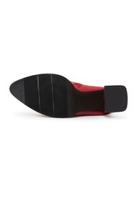 Semelle d’une chaussure en cuir rouge avec semelle en caoutchouc noir texturée et talon carré bas vue de dessous sur fond blanc.