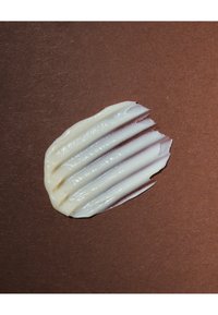 Tache de crème blanche avec des crêtes texturées sur une surface marron.