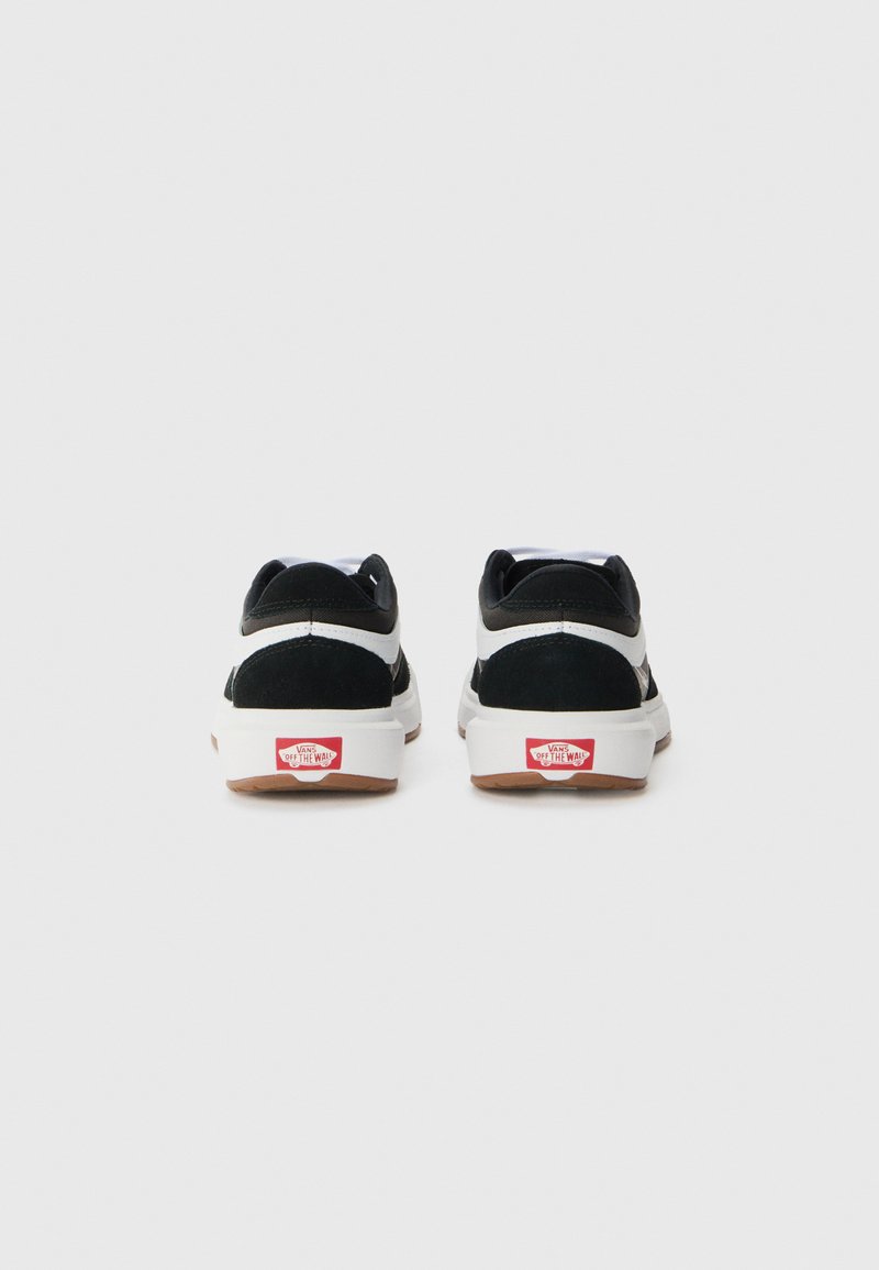 Schwarz-weiße Sneakers mit einem Obermaterial aus Wildleder und Canvas, runder Zehenpartie, Gummisohle und rotem "Off the Wall" Branding an der Ferse.