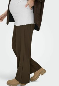 Brūnas platām kājām bikses ar gludu faktūru, kopā ar krēmveida ribotu topu un bēšām potīšu zābakiem ar biezāku, teksturētu zolīti.