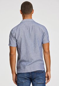 Korte mouwen, lichtblauw button-up shirt in een gestructureerde stof. Beschikt over een standaard kraag en een rechte zoom, gecombineerd met donkerblauwe jeans.
