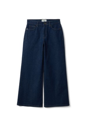 Donkerblauwe wijde denim jeans met knoopsluiting aan de voorkant, riemlussen en voorzakken, plat gelegd op een witte achtergrond.
