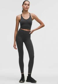 Zwart sportief crop top en leggings, met een gladde textuur, slanke pasvorm en naadloos ontwerp, gecombineerd met zwarte sneakers.